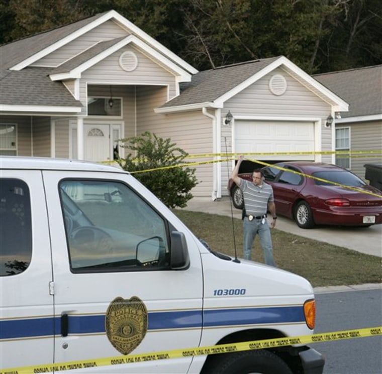 A Tallahassee investigator lifts police tape to pass under at a home where a woman and three children were slain on Saturday in Tallahassee, Fla. A woman and three young children were found killed at a violent crime scene and homicide detectives were out looking for whoever might have had a reason to harm them, police said. 